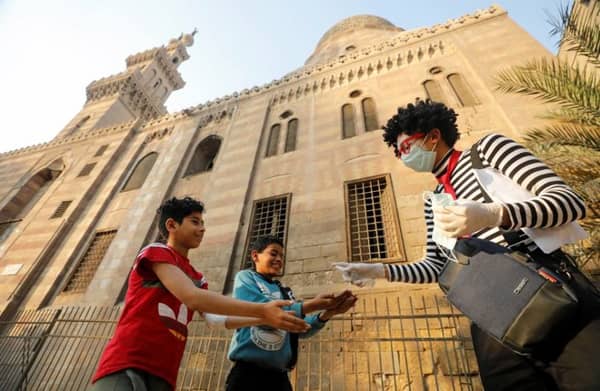 Egyptian clown Ahmed Naser, helps children to spray disinfectant before making an entertainment performance to courage them to put on face masks as a preventive measure amid concerns about the spread of the coronavirus disease (COVID-19), in Islamic Cairo, Egypt April 13, 2020. Picture taken April 13, 2020. REUTERS/Mohamed Abd El Ghany