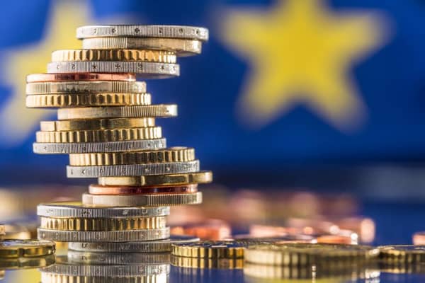 Tower with euro coins and flag of European Union in the background.