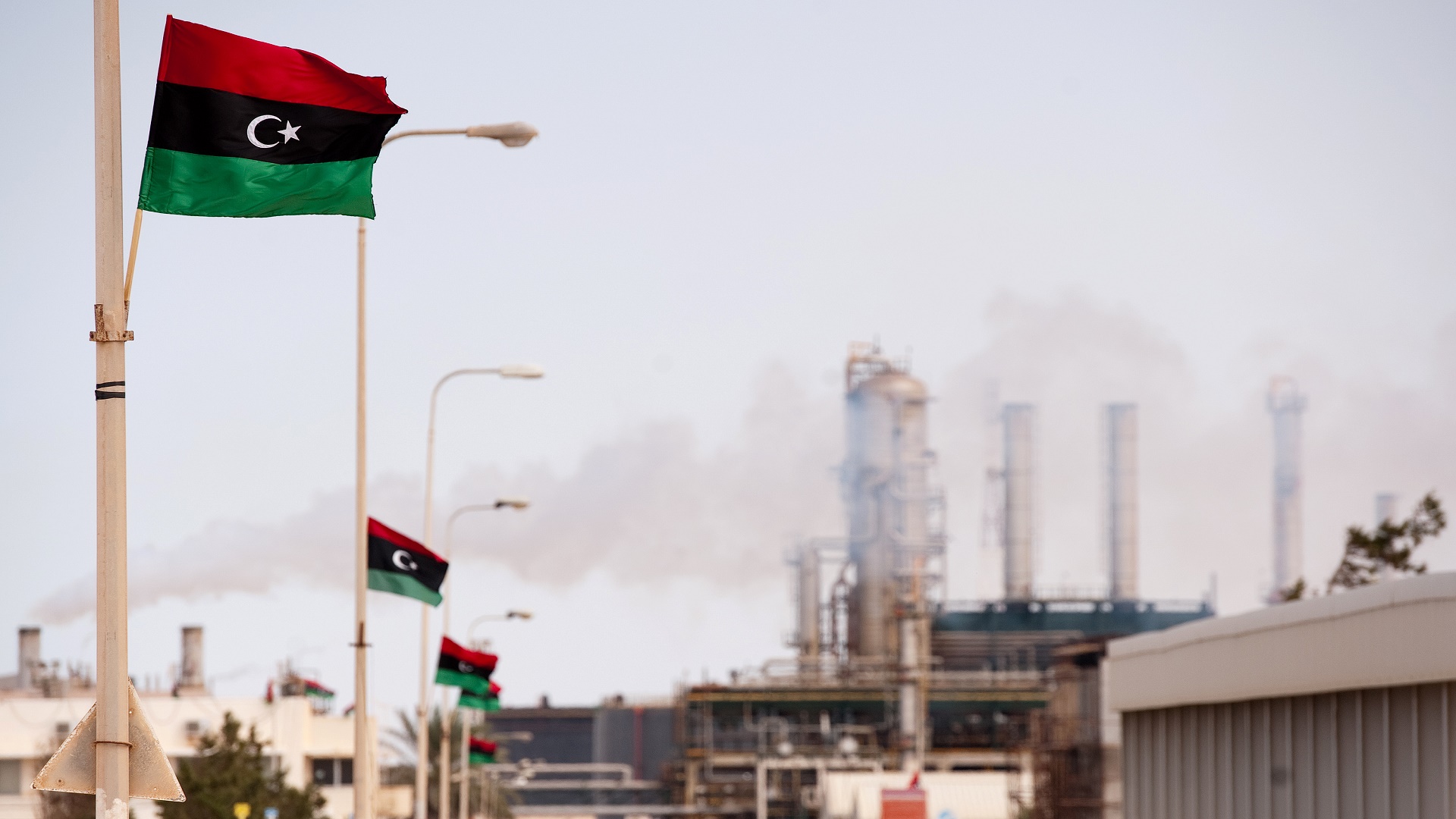 The new Libyan flag flutters outside an oil refinery in Zawiya on September 23, 2011. Total SA's Libyan joint-venture is set to restart oil production at its 40,000 barrels-a-day in Al-Jurf offshore field. Most of Libya's output of 1.7 million barrels a day was shut down after the revolution erupted in February.  AFP PHOTO/Leon Neal (Photo credit should read LEON NEAL/AFP/Getty Images)